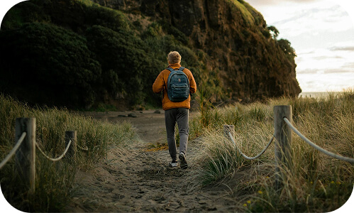 NZ employee enjoying time off work walking along a track through the beach sand dunes in Piha